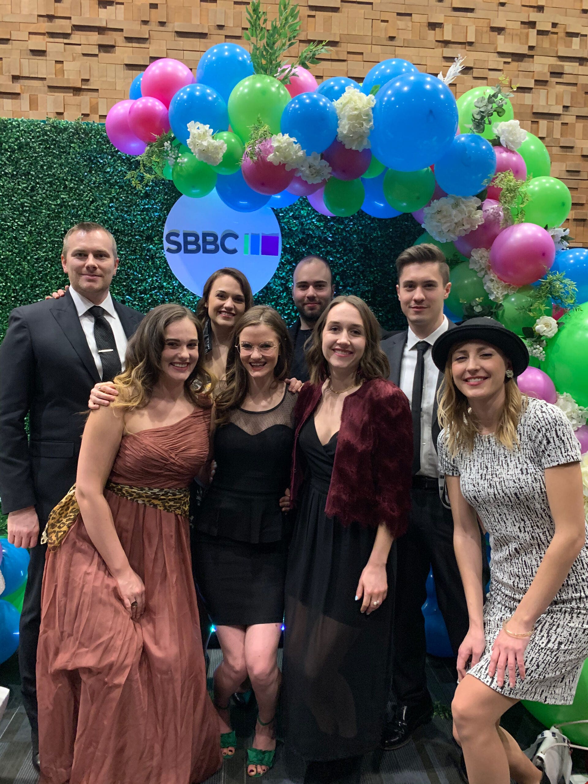 Twirling Umbrellas team members dressed up at an award event, posing together against a colourful, celebratory backdrop.