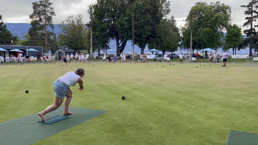 A shot of Twirling Umbrellas employee Carla lawn bowling at On the Lawn